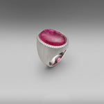 A BUNDA 'Corvus' ring in 18 carat white gold, set with a cabochon cut Tourmaline, surrounded with a line of thread set diamonds. The white gold setting has an elegant brushed finish.  Weight of Tourmaline: 1 =24.15ct.  Characteristics of diamonds: 45 = 0.25ct, F colour, VS clarity.  Total weight: 21.38g