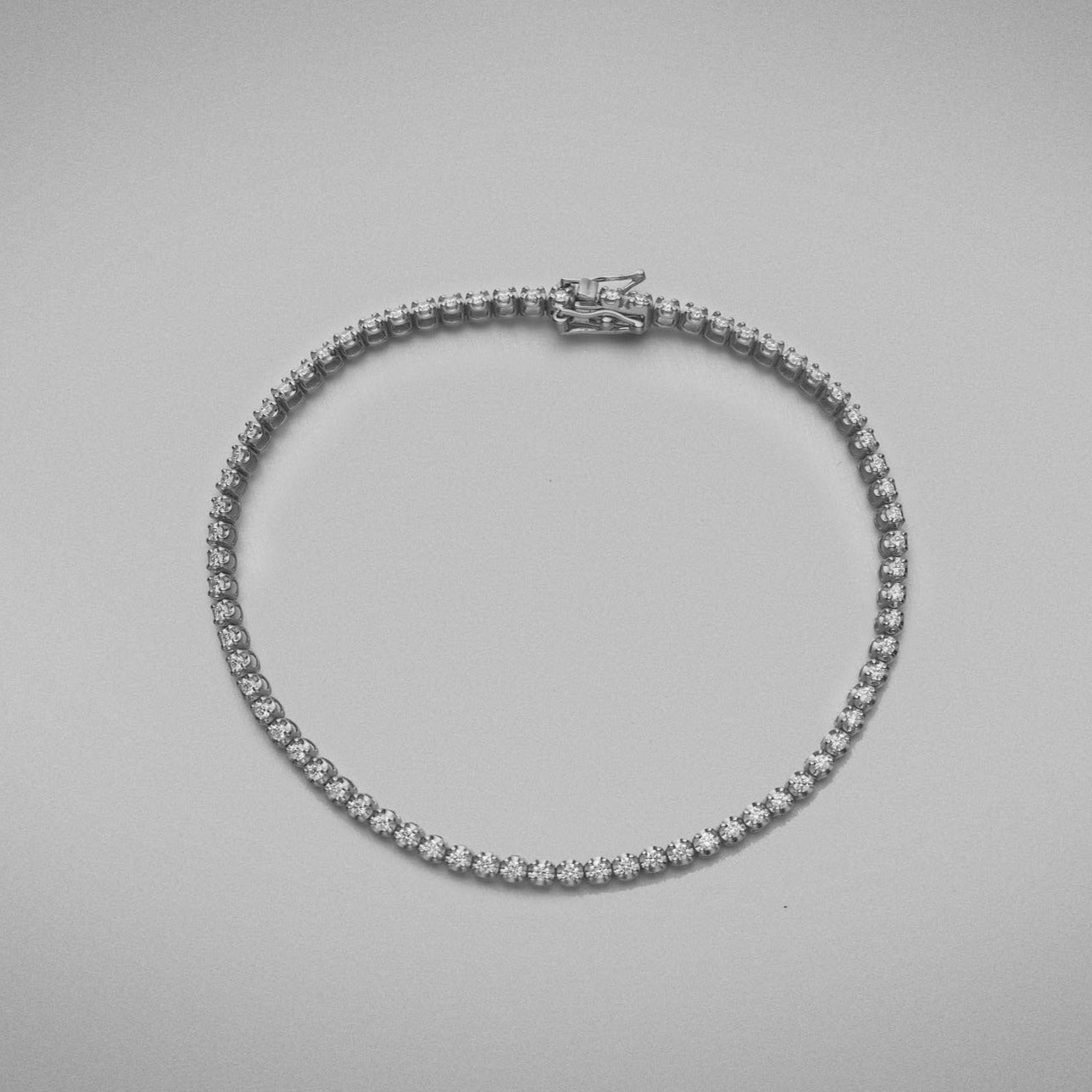 A BUNDA 'Tennis' bracelet in 18ct white gold. The bracelet is set with round brilliant diamonds in castle claw settings. Bracelet is stamped 'BUNDA'.  Characteristics of Round Brilliant Cut Diamonds: 87 = .69ct, F colour, VS Clarity  Total weight of bracelet: 5.19 grams